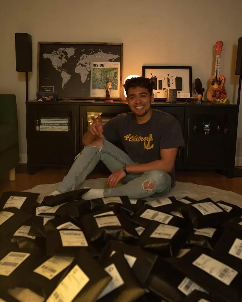 Cristian, the Wedibox founder, sitting on the floor surrounded by Wedibox packages with shipping labels