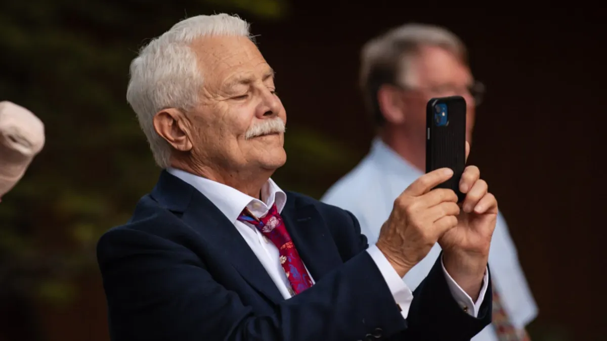 Elderly gentleman using his phone to capture and share moments at a digital wedding