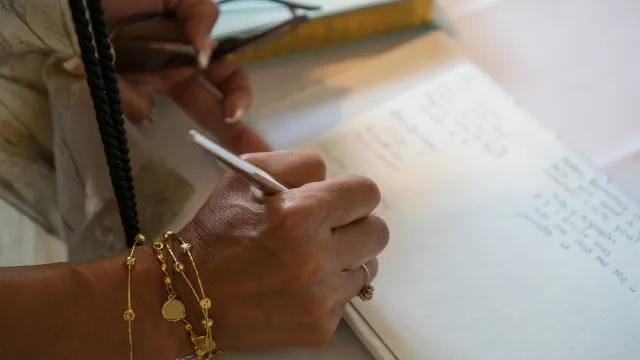 Guest hand signing a traditional wedding guest book, capturing personal wishes and memories
