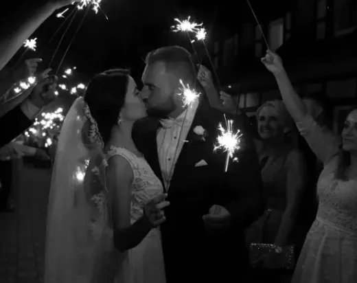 Couple kissing during their sparkler exit, shared by a wedding guest