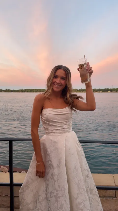 Bride toasting at sunset by the water at a destination wedding