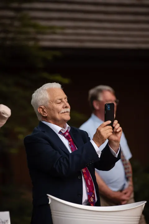 Elderly guest smiling while taking a photo at a wedding